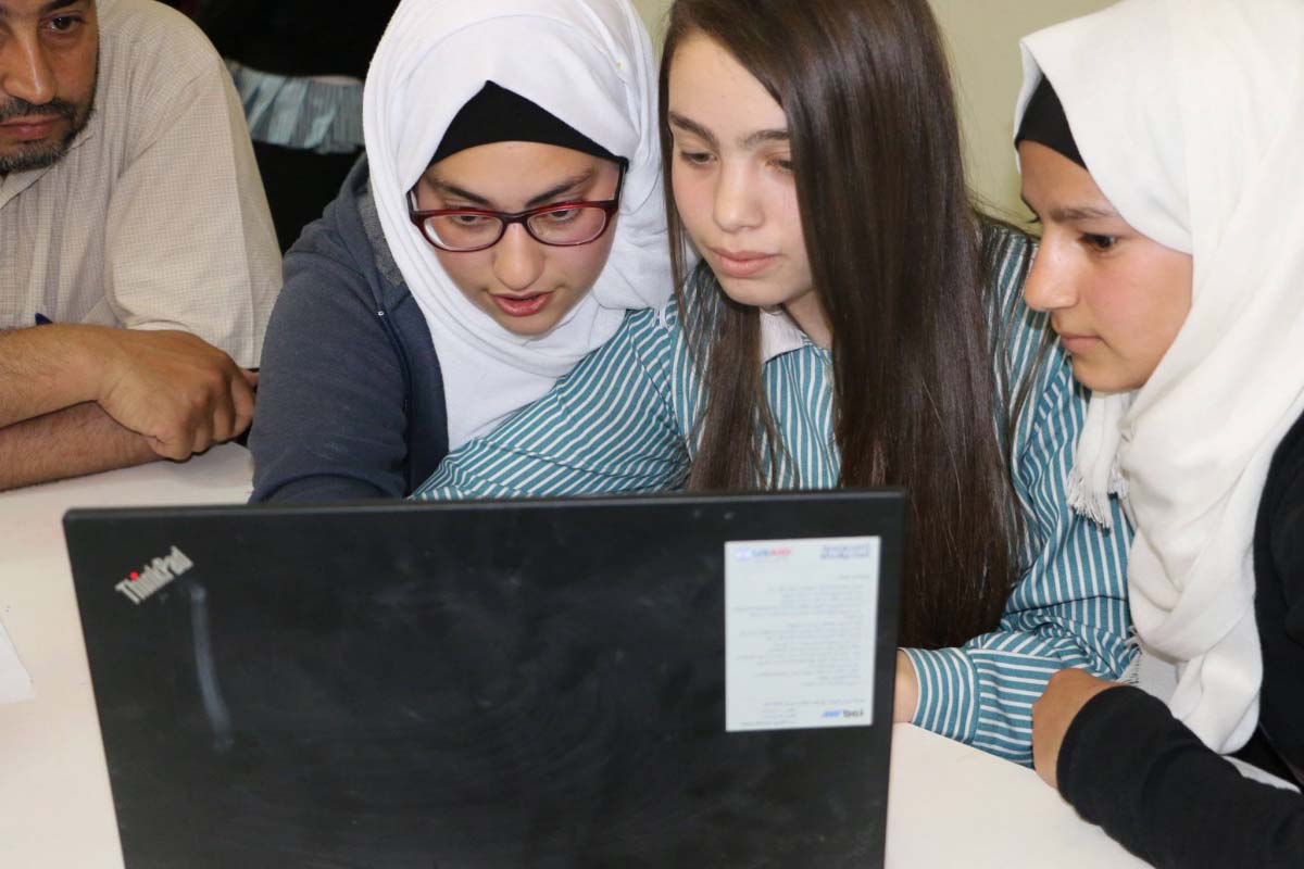 طالبات شابات في برنامج تطوير القيادة والمعلمين (LTD) ينظرن معًا إلى الحاسوب المحمول