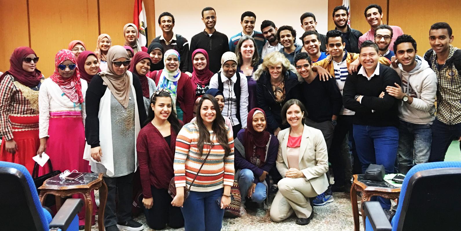 مجموعة كبيرة من طلاب الجامعات المصريين يتجمهرون معًا ويبتسمون أمام الكاميرا