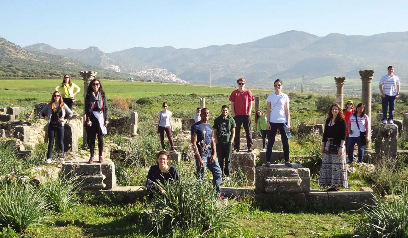 Students stand on columns and the ruins of the Roman city of Volubilis in Morocco