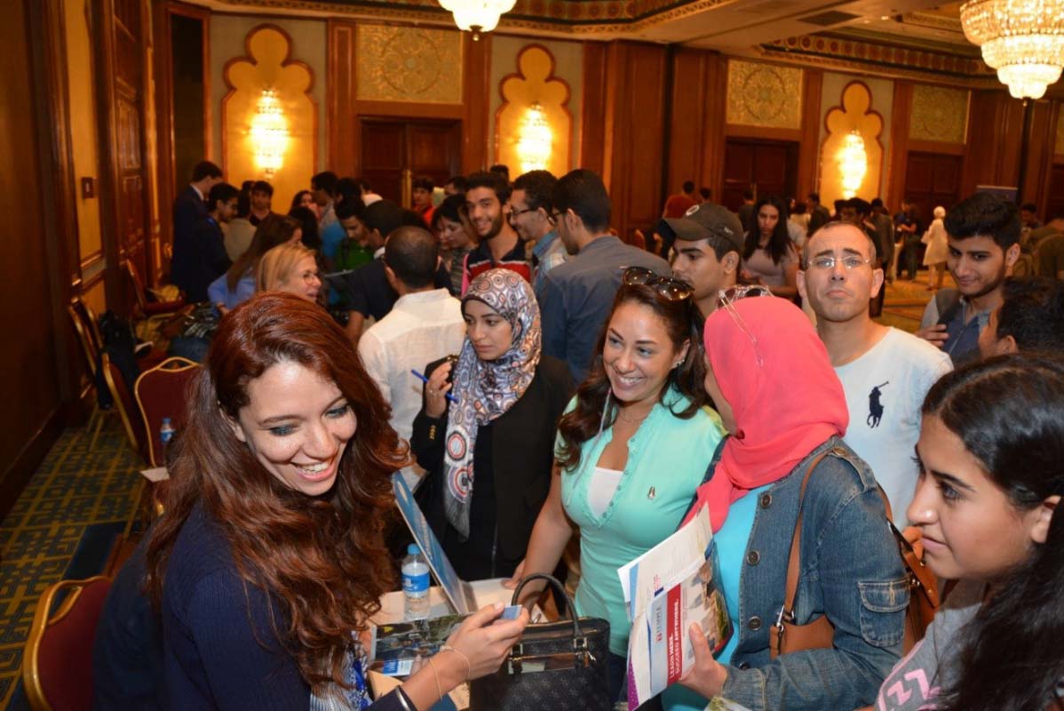 A group of women talk to a woman behind a table at the NAFSA fair