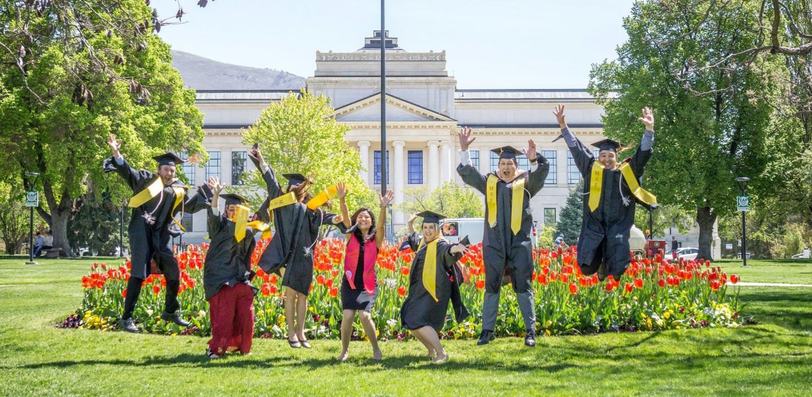 Group of Graduating students jumping in their caps and gowns