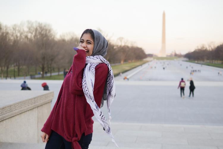 A young woman in a Palestinian kuffiyeh laughs near the Washington Monument