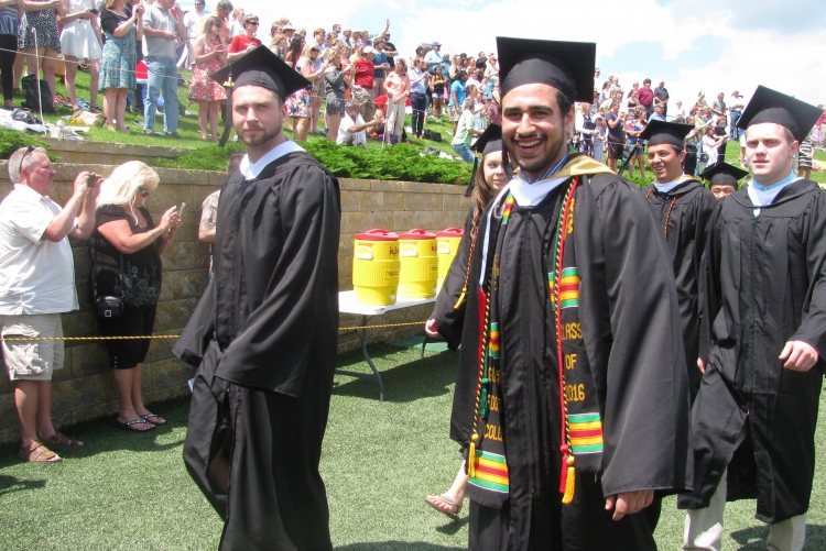 Graduates in caps and gowns walk by