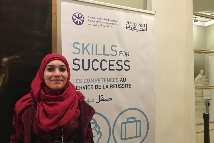 Women smiles in front of a sign that reads “Skills for Success”