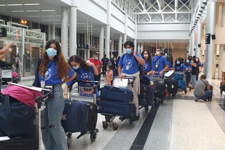 Students moving through the airport with their bags