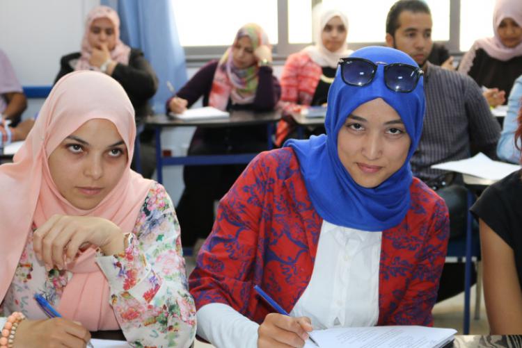 Libyan English teachers write at desks in a classroom during a PCELT training