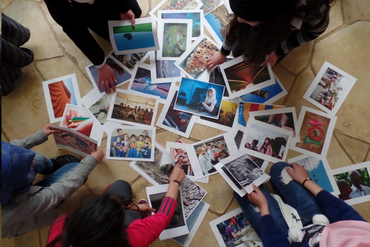 Female students look at a collection of printed photographs