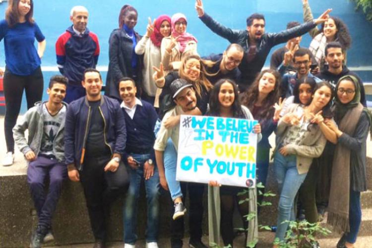 A group of Moroccan students smile and hold a sign that says “We Believe in the Power of Youth” 