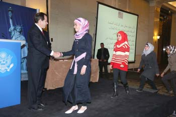 Students walk across a stage to shake a man’s hand