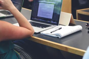 Photo of person sitting in front of laptop