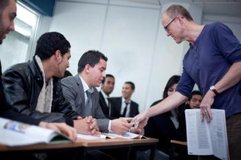 A teacher talks to students sitting at desks