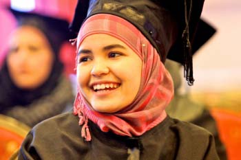 Female graduate smiles in cap and gown