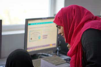 AMIDEAST Yemen Training Coordinator is helping a female Tawtheef recipient while doing an assignment on her computer.