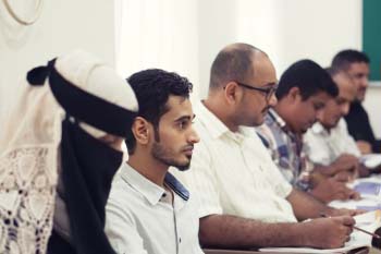 Yemeni high school students listening to an educational adviser in a classroom