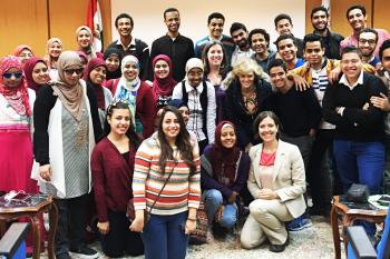 مجموعة كبيرة من طلاب الجامعات المصريين يتجمهرون معًا ويبتسمون أمام الكاميرا