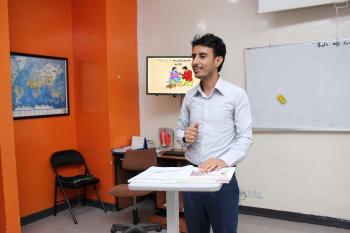 An EFL instructor is standing explaining a lesson in a classroom at AMIDEAST Yemen 