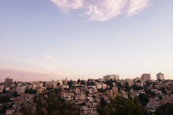 The skyline of Amman at sunset the buildings in the distance and the sky is prominent and a rosy color at the horizon but clear blue at the top.