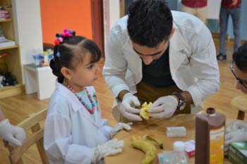 A man and a young girl study an animal bone