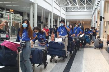 Students moving through the airport with their bags