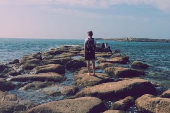 Student walks on rocks jutting into the Atlantic Ocean in Rabat, Morocco