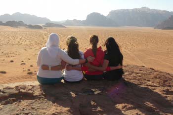 Four women sit on a rock in Wadi Rum, Jordan