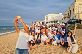 One individual takes a selfie with a group on the beach in Tangier