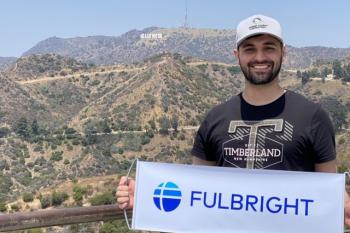 College student in front of Hollywood sign in Los Angeles holding banner with Fulbright program logo