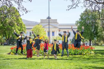 Group of students jumping in their gap and gown