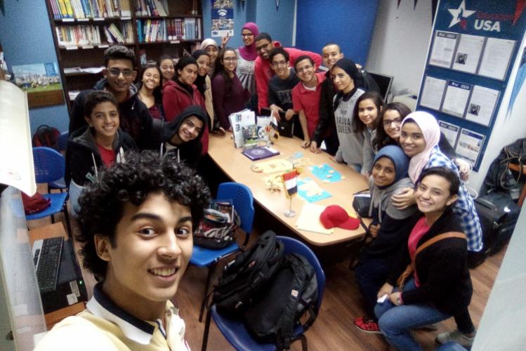 A group of students pose for a selfie while sitting around a table