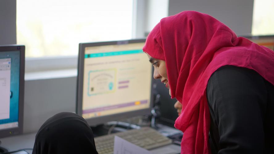 AMIDEAST Yemen Training Coordinator is helping a female Tawtheef recipient while doing an assignment on her computer.
