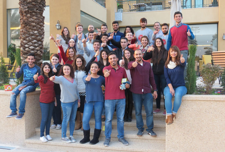 Large group of young adults outside, smiling and giving a thumbs up