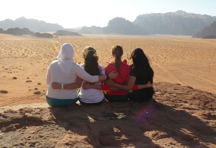 Four women sit on a rock in Wadi Rum, Jordan