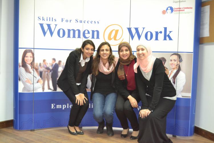 Female students stand in front of a sign that reads “Skills for Success: Women at Work”