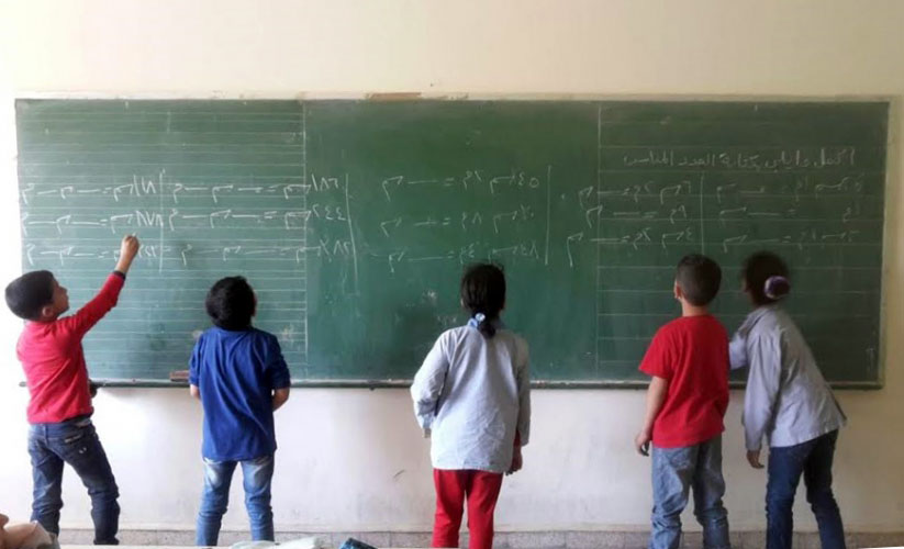 Children writing in Arabic on a blackboard as part of the Ana Iqra project