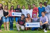 A group of students smile and pose while holding Fulbright signs