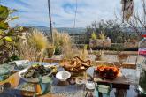 A table is laden with many different dishes. The table is on a balcony overlooking hills in Tunis