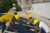 Four students in the Nahdhat Shabab Project wearing hard hats and working on solar panels