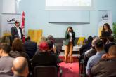 A women speaks into a microphone while the audience watches her