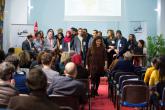 A group of BLADI participants stand on stage while one walks down towards the audience