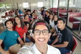 A group of students eat in a restaurant and smile