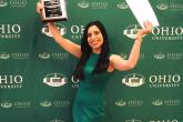 Female student holding up awards in front of Ohio University backdrop