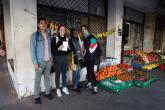 Students pose in front of a hanout with the fruits and vegetables.