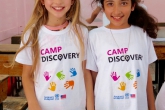 Two young female students in Camp Discovery shirts smile