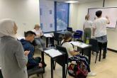 From the teacher's vantage point, two students write on the board in an Arabic class.