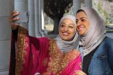 Two women pose for a selfie while one is in traditional Bahraini dress