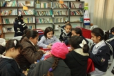 طالبات شابات يجلسن على طاولة في مكتبة حيث يقرأن ويكتبن