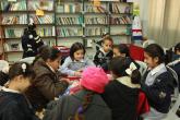 Young female students sit at a table in a library, reading and writing