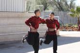 Two young males hold each other's arms while performing a Dabke dance