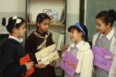 Young female LTD students hold signs with Arabic text written on them while talking to each other