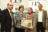 Two women are holding a new laptop in front of a sign that has the LTD logo on it, two men also pose with them